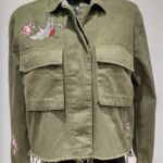 Olive green cropped military-style jacket with embroidered bird and floral designs on the sleeves and chest, featuring two large front pockets and a raw hem.